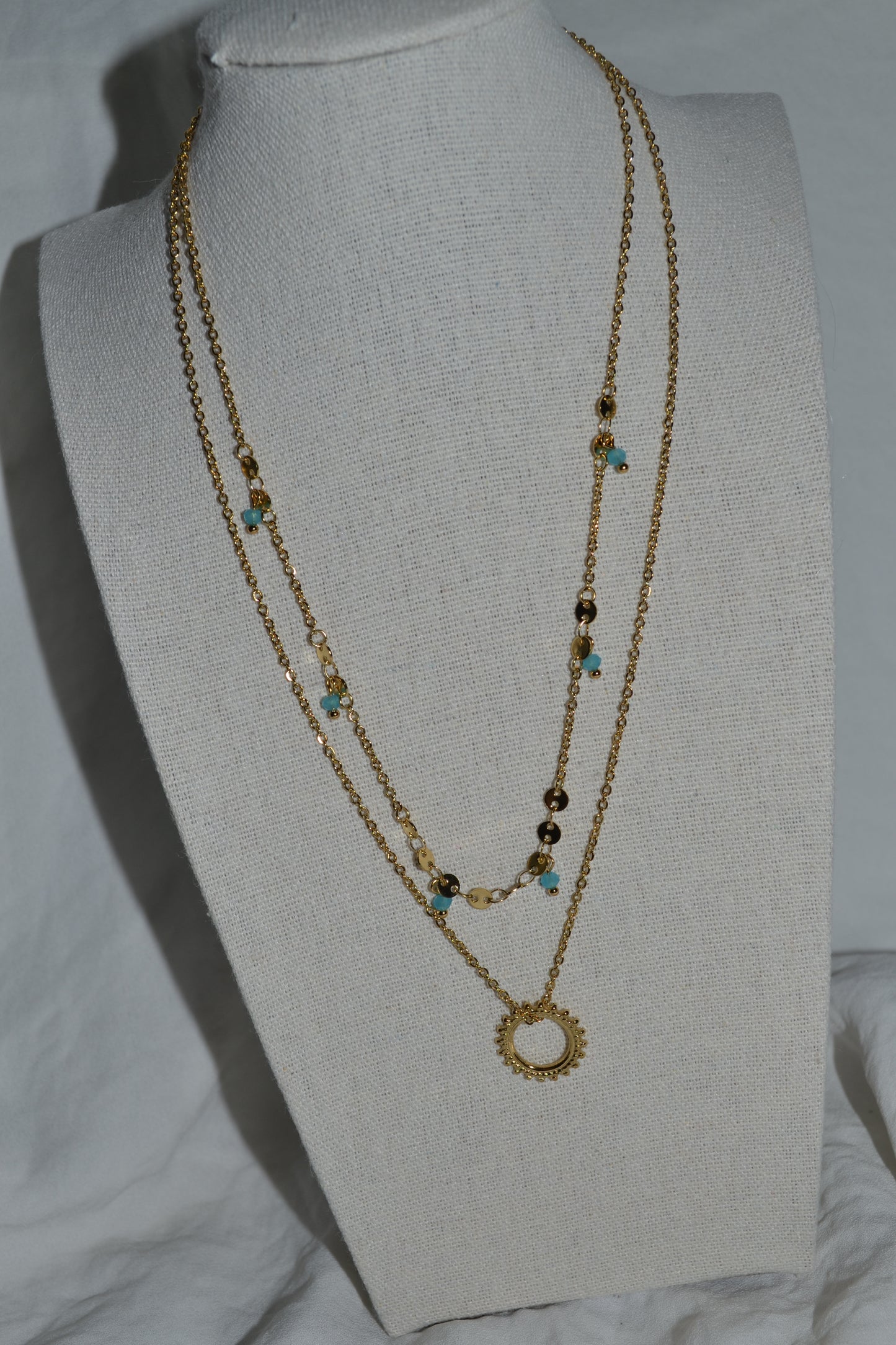 Collier double chaîne dorée avec pendentif soleil et pierre bleue